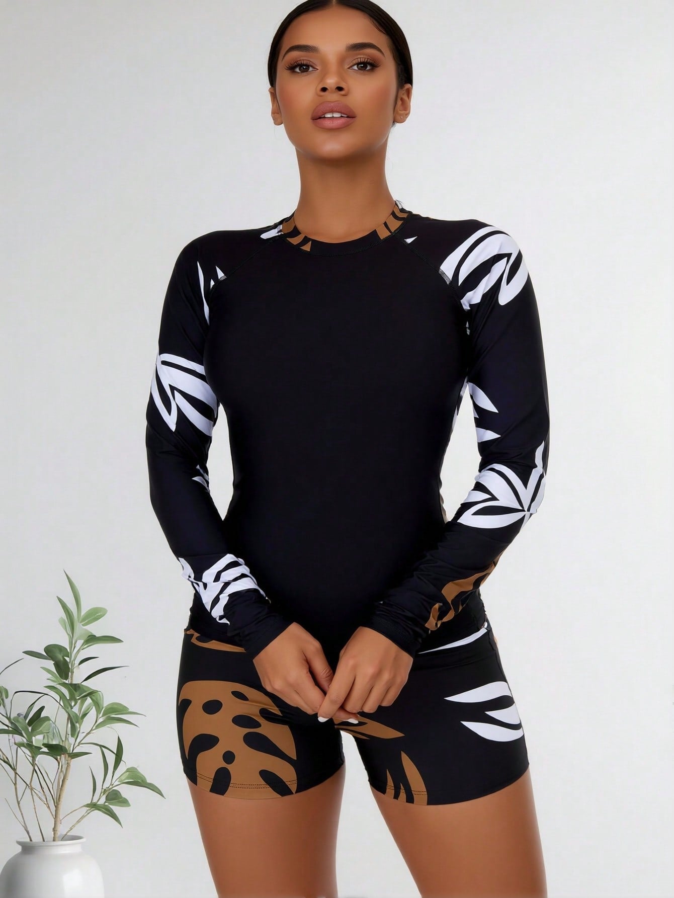 Black long-sleeve rash guard top with tan-and-brown abstract leaf boy shorts