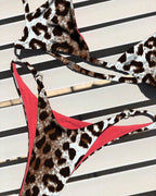 Leopard-print one-piece bikini with red piping, halter neckline, and side tie straps