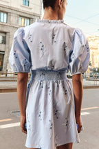 Light blue women's spring dress with puff sleeves, smocked waist at back, and navy animal print
