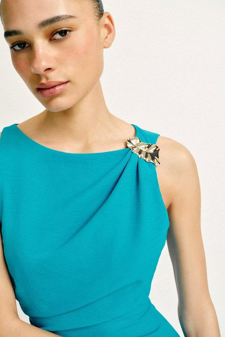 Teal sleeveless dress with draped neckline and decorative shoulder detail