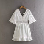 White summer dress with lace V-neck, ribbon tie, and bell sleeves