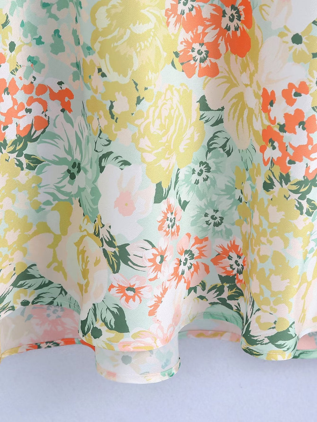 Floral maxi dress fabric close-up with pastel green, yellow, and orange blooms