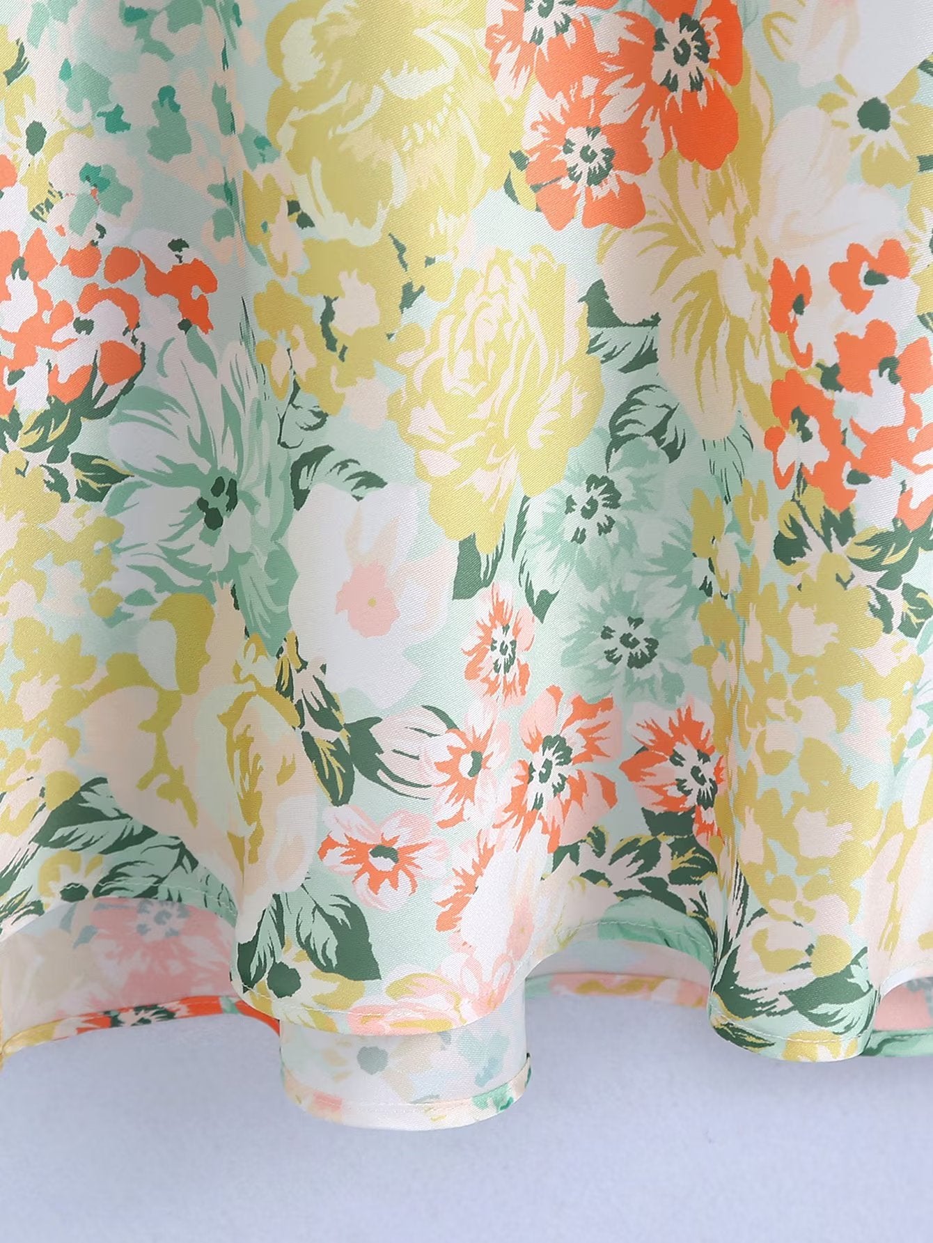 Floral maxi dress fabric close-up with pastel green, yellow, and orange blooms