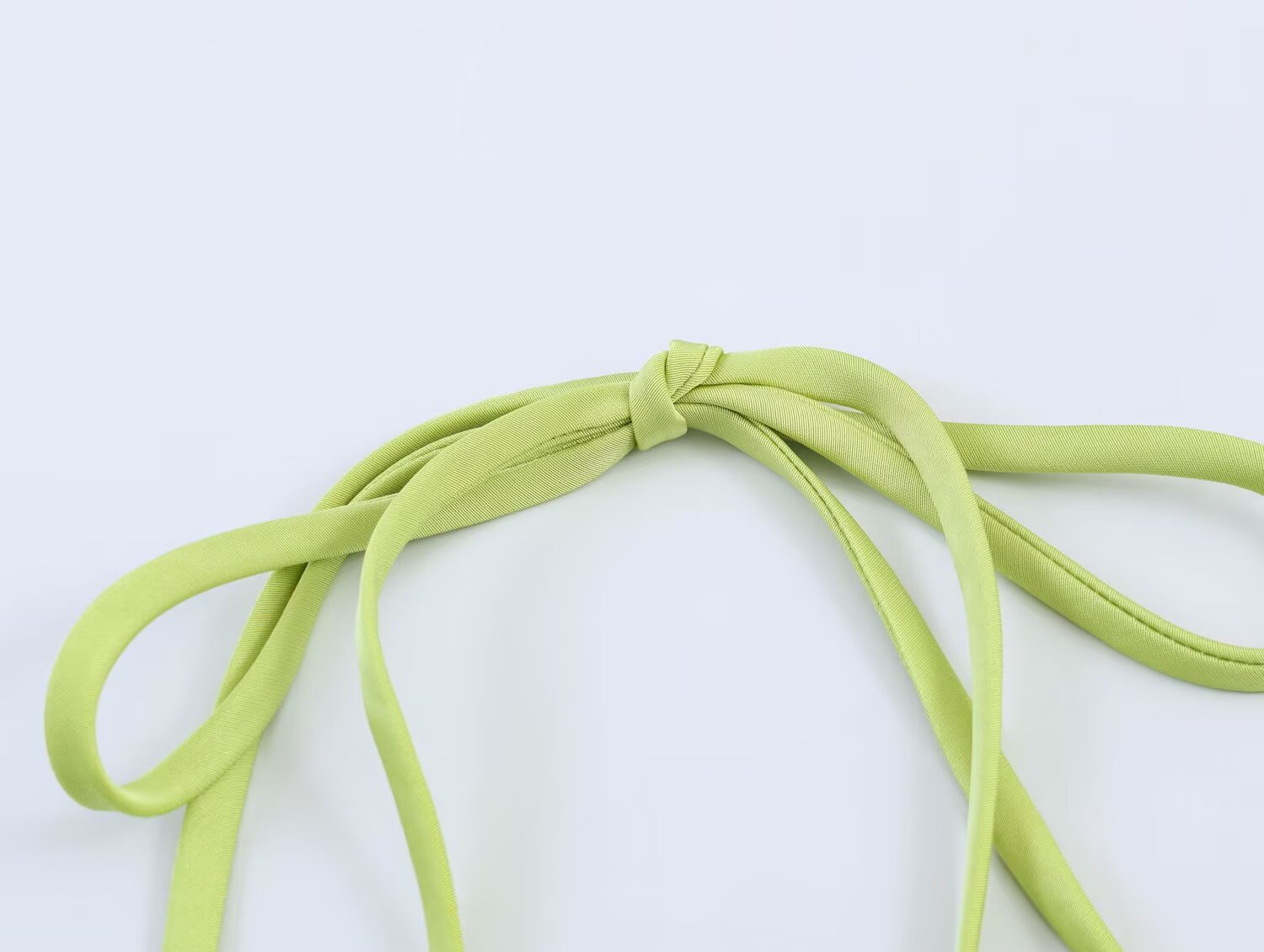 Green tie straps and bow detail at satin bodice, close-up