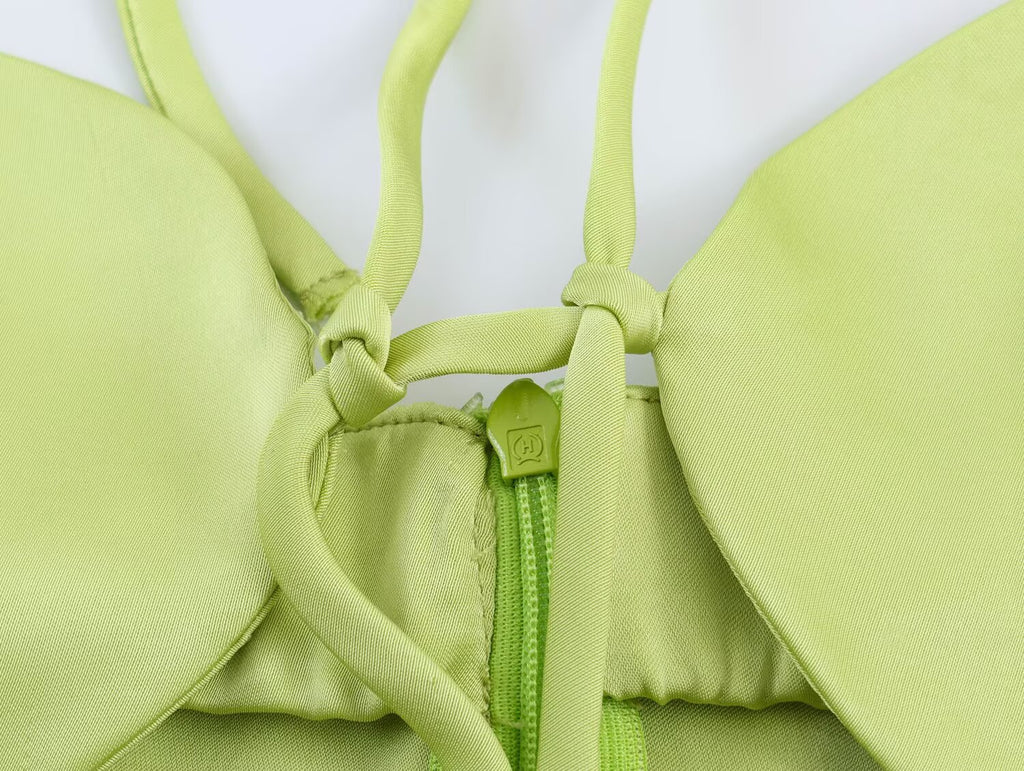 Green satin bodice with bow accents and exposed zipper, close-up