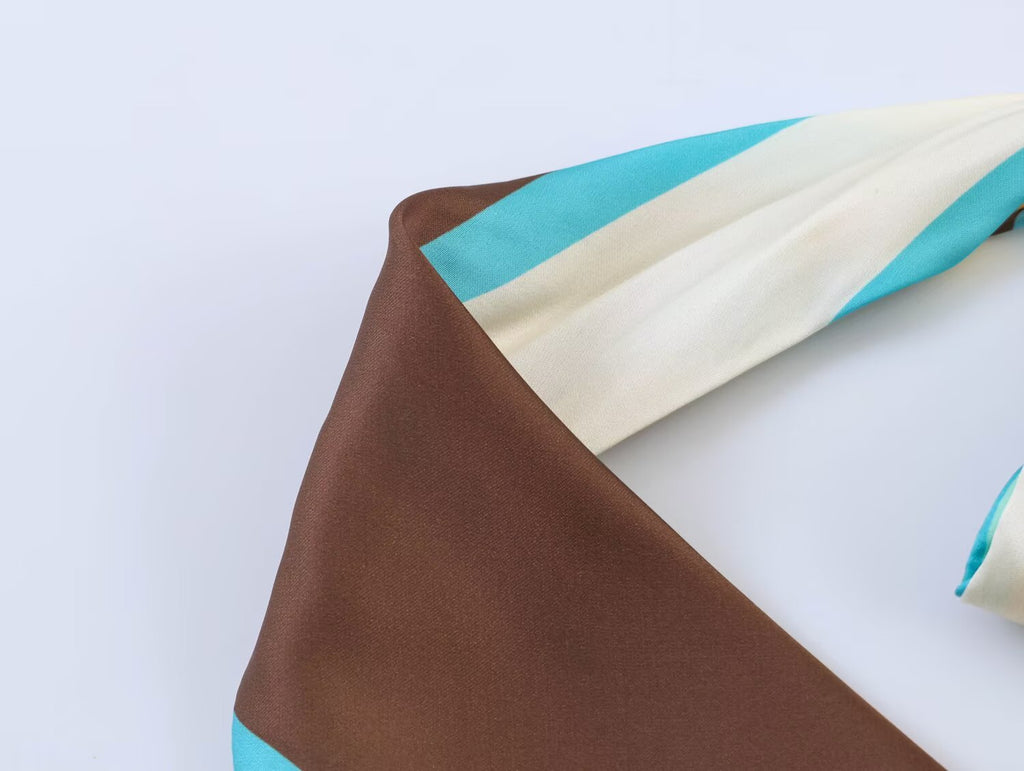 Geometric pleated halter dress with brown and teal panels, draped neckline