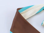 Geometric pleated halter dress with brown and teal panels, draped neckline