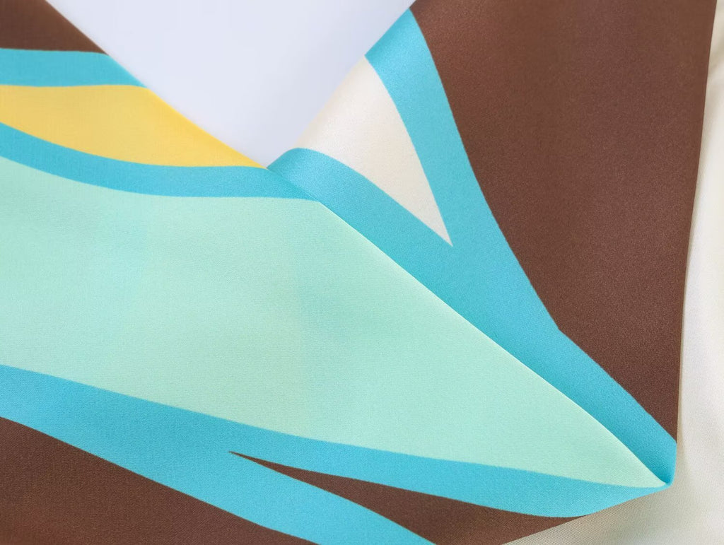 Pleated fabric detail with teal and brown geometric stripes at hemline