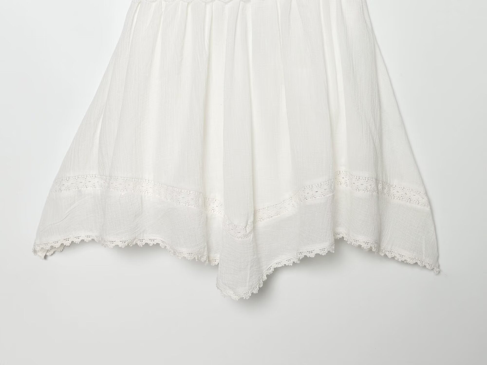 White mini summer dress with pleated skirt and scalloped lace hem