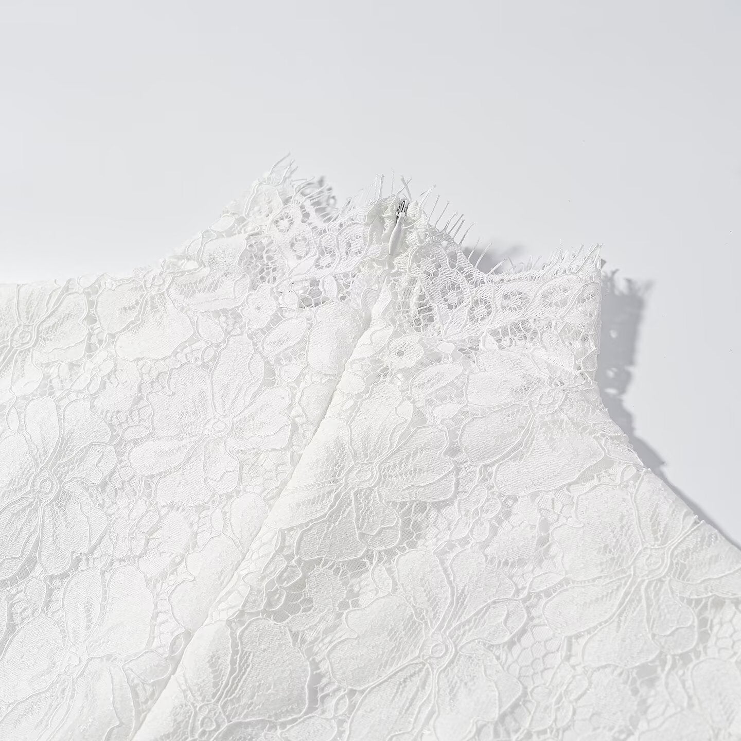 Close-up of white lace bodice with high neckline and scalloped detailing