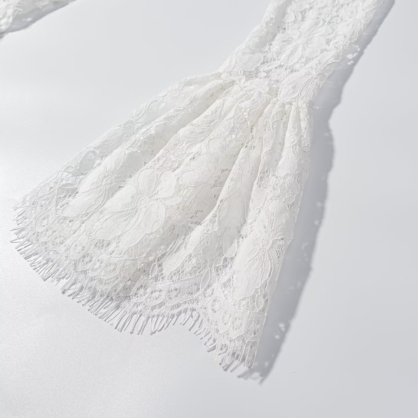 White lace sleeve and upper skirt detail with fringed edges and flare