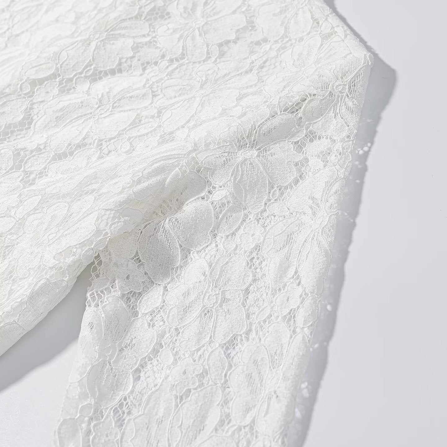 White lace side panel close-up with textured floral pattern