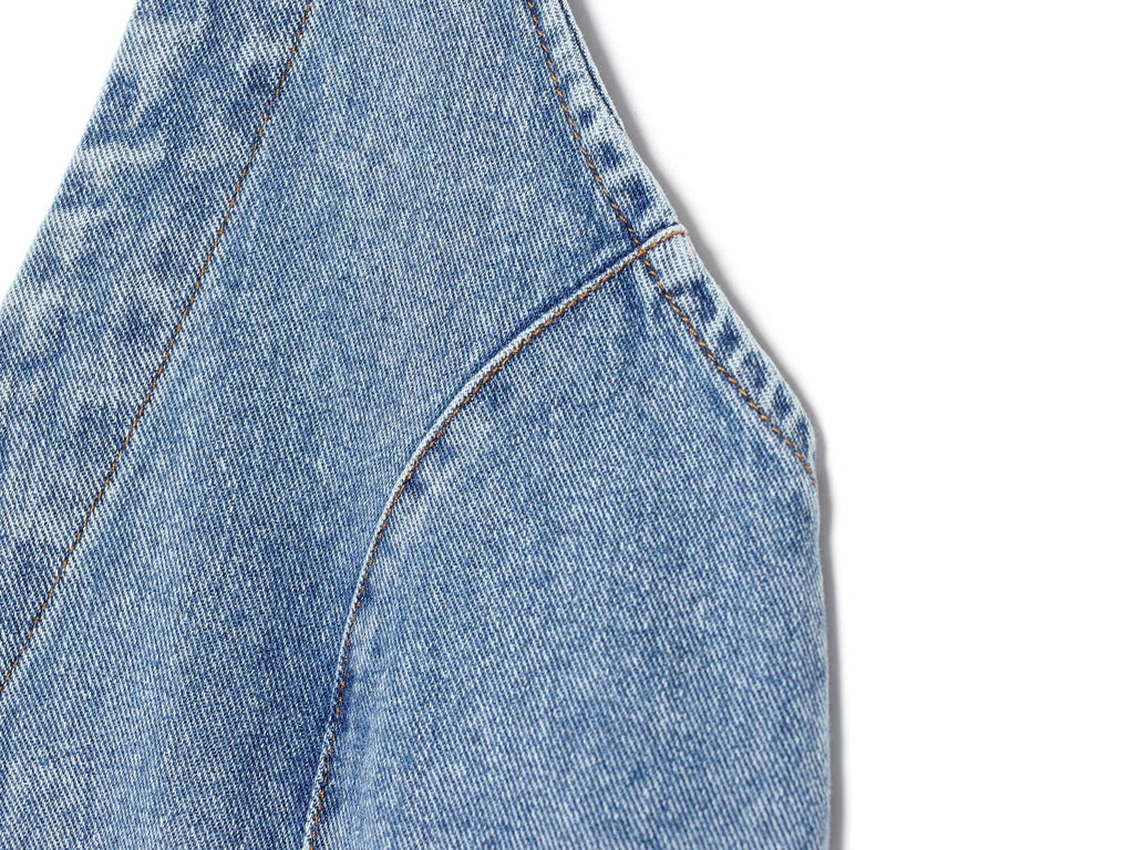 Close-up of blue denim halter dress seam and curved pocket edge