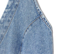 Close-up of blue denim halter dress seam and curved pocket edge