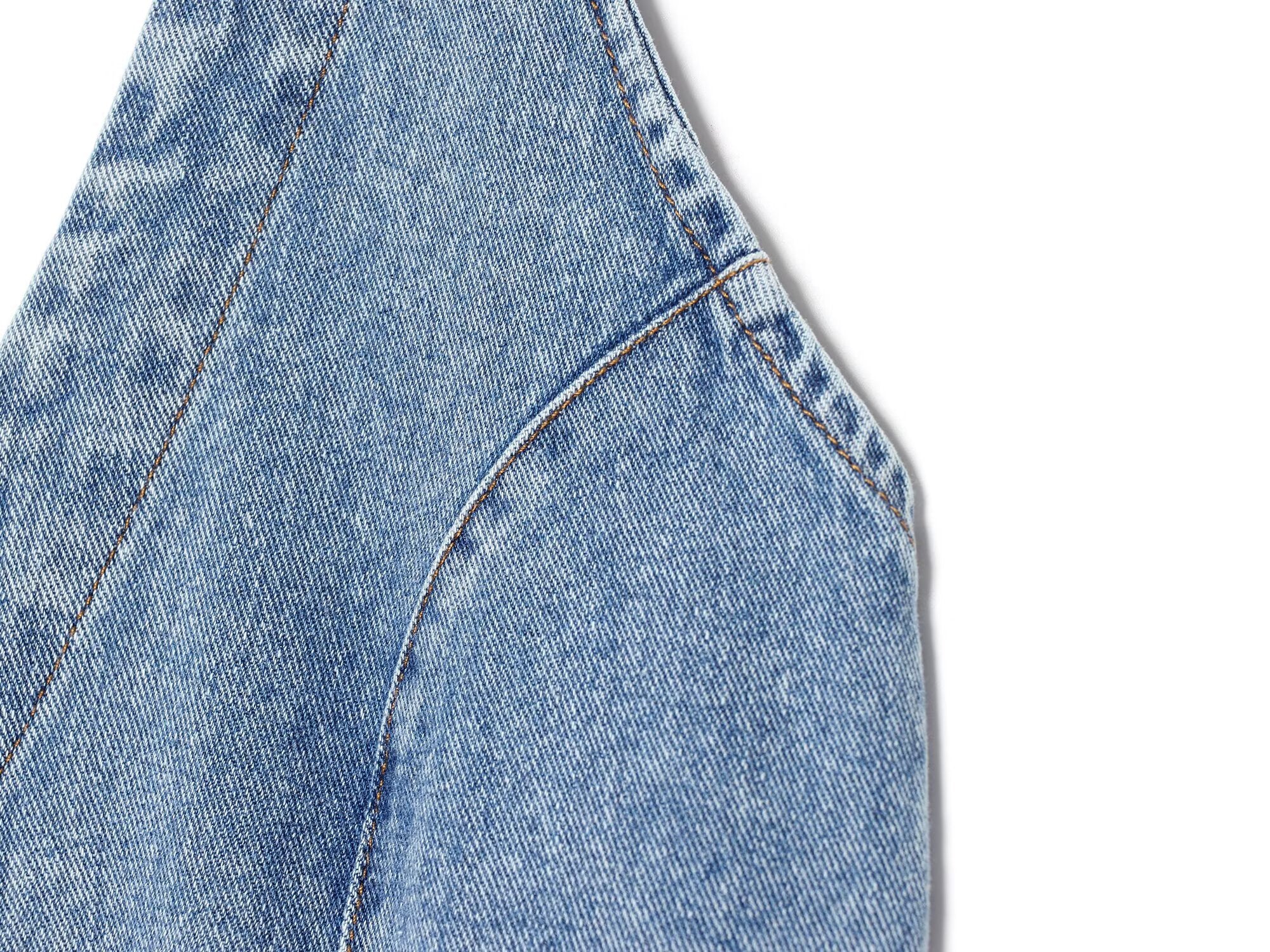 Close-up of blue denim halter dress seam and curved pocket edge