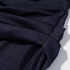 Navy blue pleated fabric with diagonal drape and stitched seam on skirt