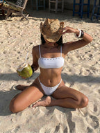 White bikini one-piece with thin straps and stud trim, low scoop front and back