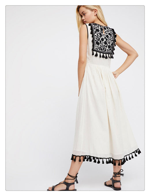 Women’s sleeveless floral dress in white with black patterned yoke and tassel trim.