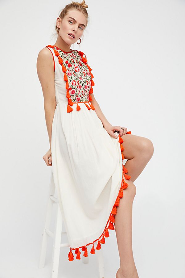 Women’s sleeveless dress, red floral bodice with tassels and white tiered skirt detail.