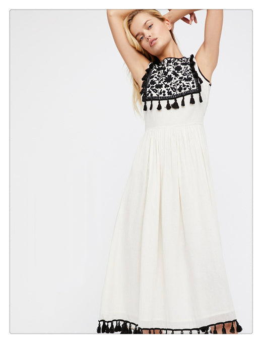 Women’s sleeveless dress with black patterned yoke and tassel trim on a white skirt.