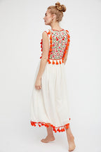 Women’s sleeveless floral dress with red patterned bodice, white skirt, red tassel accents.