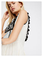 Close-up: women’s sleeveless dress with black patterned yoke and tassel shoulder trim.