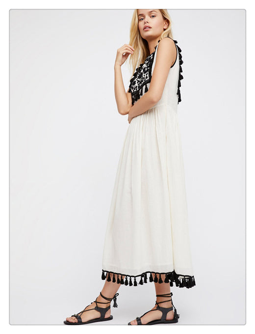 Women’s sleeveless white dress with black patterned collar and tassel trim at hem.