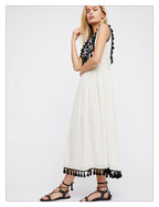 Women’s sleeveless white dress with black patterned collar and tassel trim at hem.