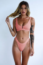 Pink one-piece swimwear with scoop neck, high-cut bottom, and center ring detail