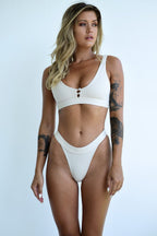 White one-piece swimwear with scoop neckline, high-cut bottom, and center ring clasp