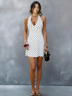 White halter V-neck mini dress with black polka dots, standing front