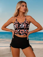 Floral halter crop bikini top with black side-tie high-waist swim shorts, hands on hips