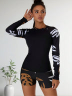 Black long-sleeve rash guard set with white leaf-print sleeves and tan abstract shorts