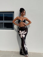 Black halter bikini with white floral print and matching long skirt, standing