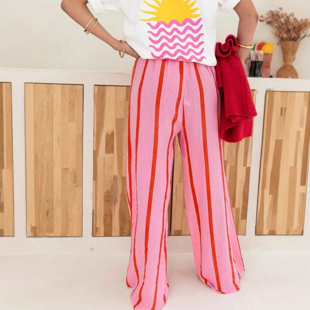 Women’s pink striped long pants with vertical orange and white stripes, full leg view