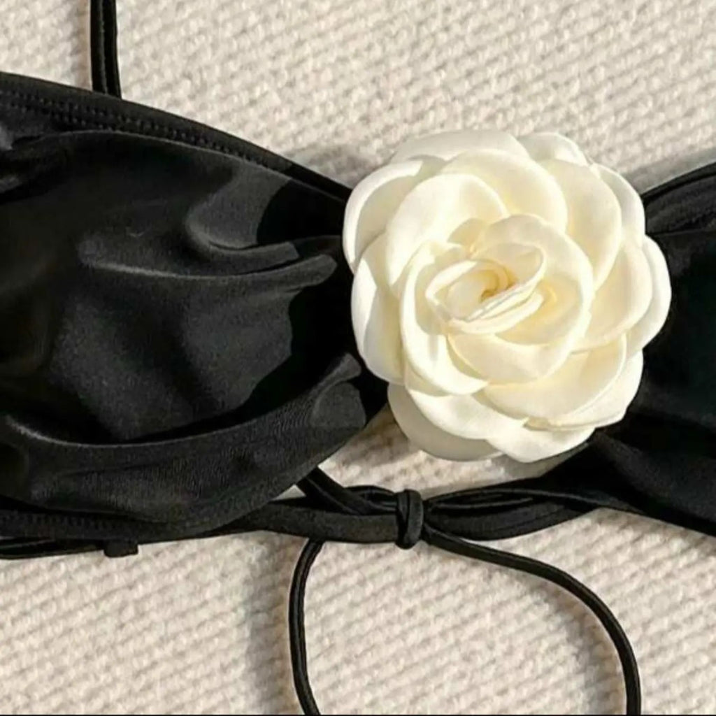 White flower embellishment on black bikini bandeau cup with tie straps