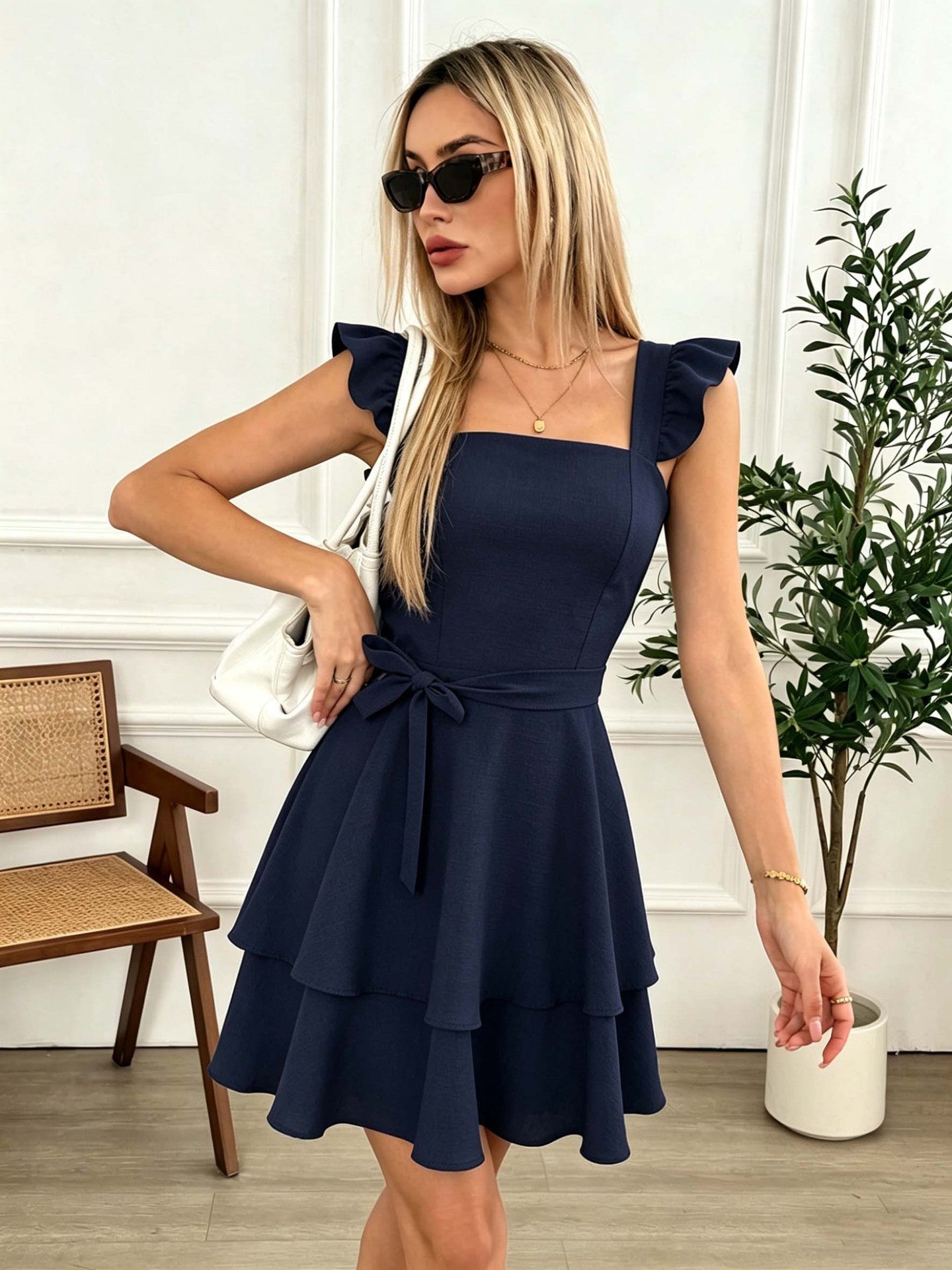 Navy blue short dress with square neckline, bow tie waist, layered ruffle hem, cap sleeves.