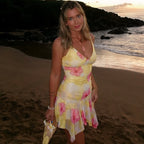Yellow floral summer dress with thin straps and layered ruffled hem, outdoor pose