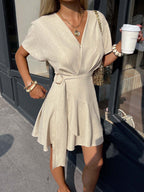 Light beige V-neck mini dress with short sleeves, waist tie, and gathered skirt
