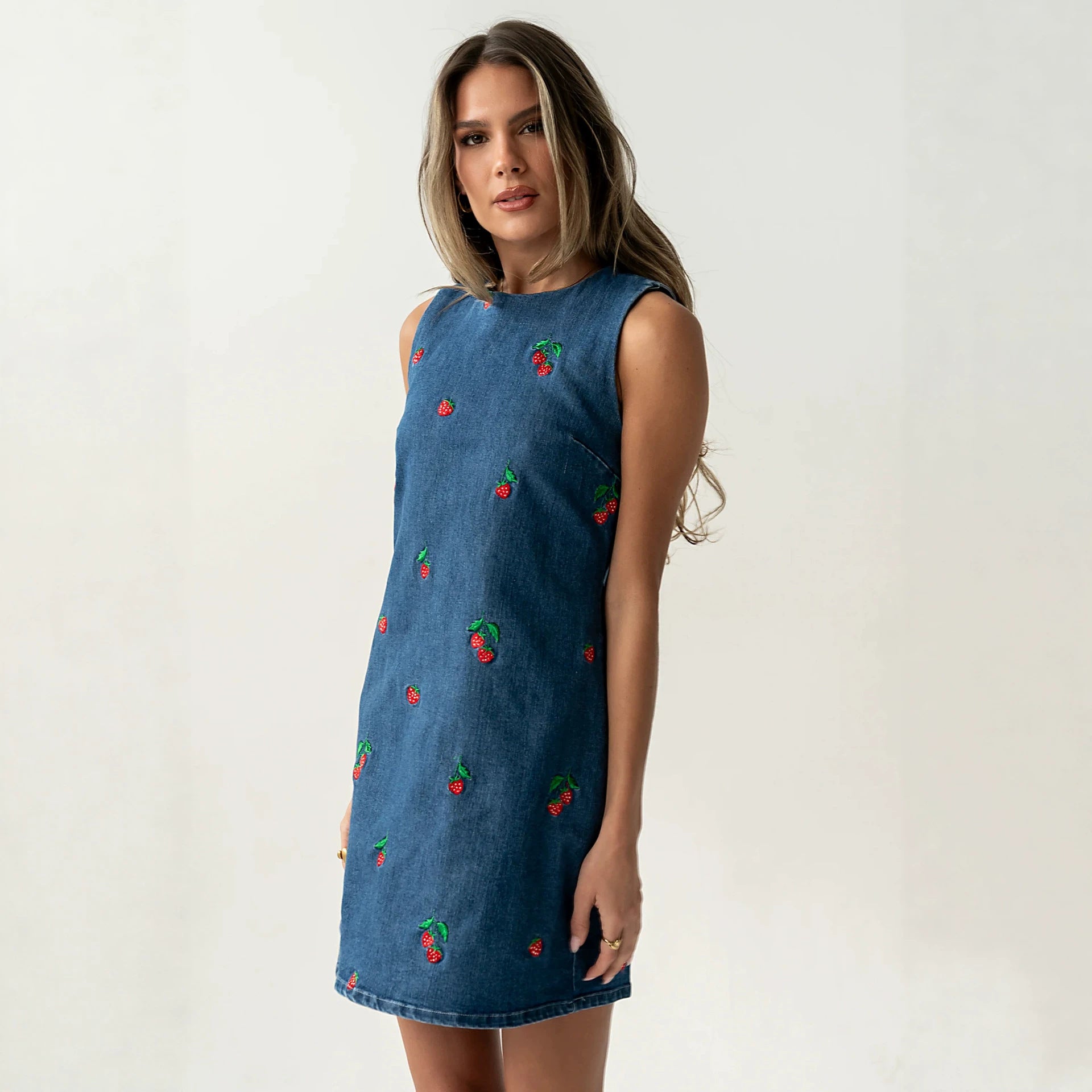 Blue denim sleeveless vest with red and green embroidery, side view, straight hem