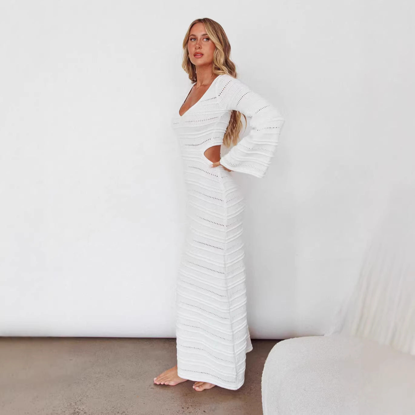 White maxi knit dress, long sleeves, V-neck, fitted column silhouette.