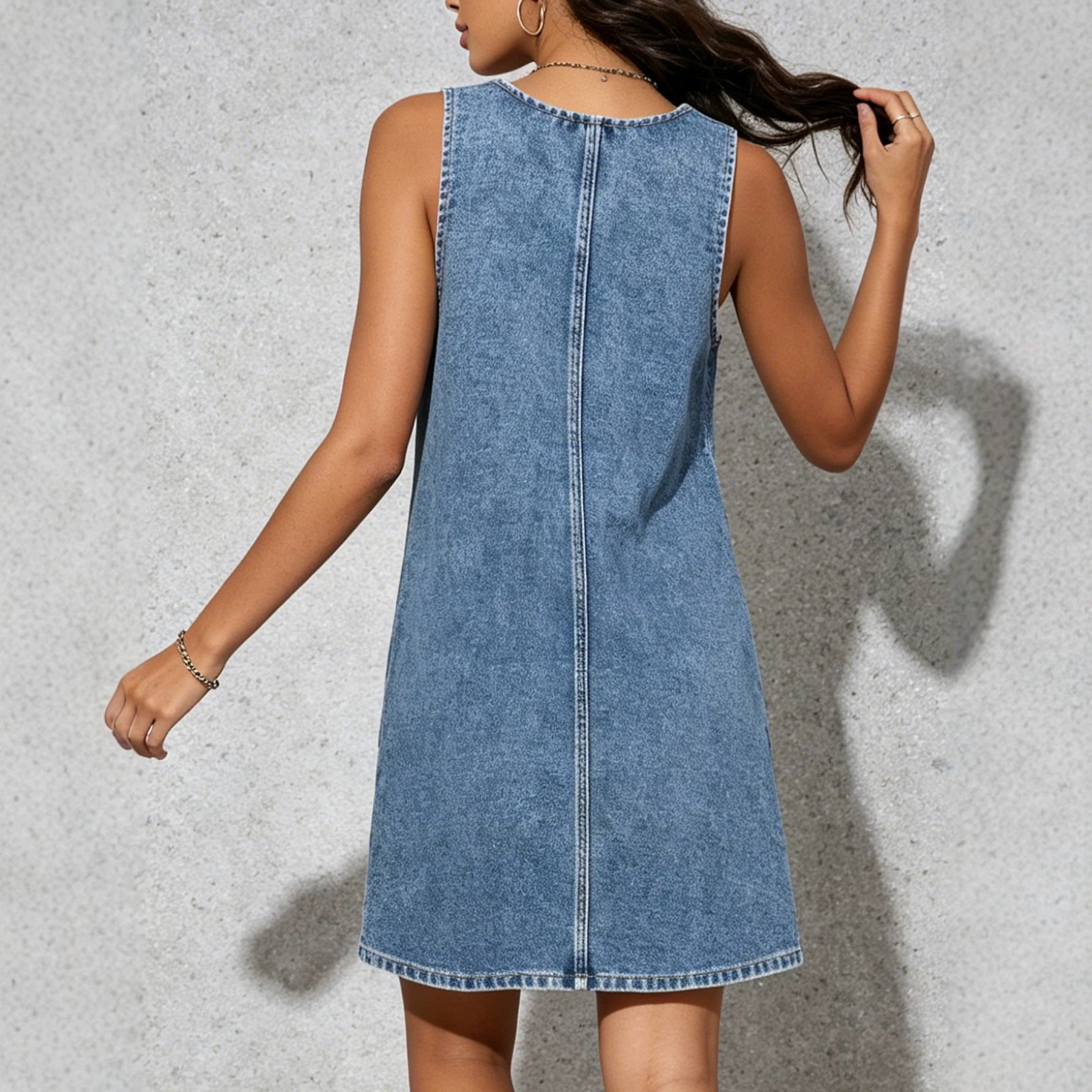 Blue denim sleeveless sling dress with central back seam and floral-embroidered hem