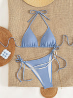 Blue backless bikini one-piece with halter ties, high-cut bottoms and pearl strand trim