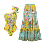 One-shoulder one-piece swimsuit and long swim skirt in bright yellow and teal ornate floral print