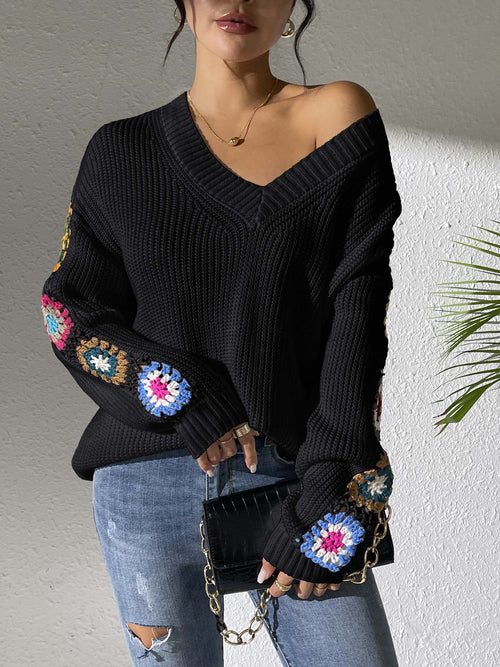 Black V-neck knit sweater with bright floral embroidery on the sleeve cuffs