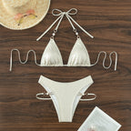 White glitter triangle bikini top and high-waist bottoms with tie closures, laid flat