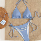 Blue backless bikini one-piece with halter triangle top, tie straps, pearl strand detail