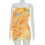 Pleated sleeveless mini dress on mannequin, yellow with blue cloud-pattern strapless bodice