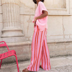 Women’s pink striped long pants with vertical orange and white stripes, side profile