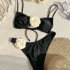 Black bikini set with ruched bandeau top and high-cut bottoms, white flower embellishment